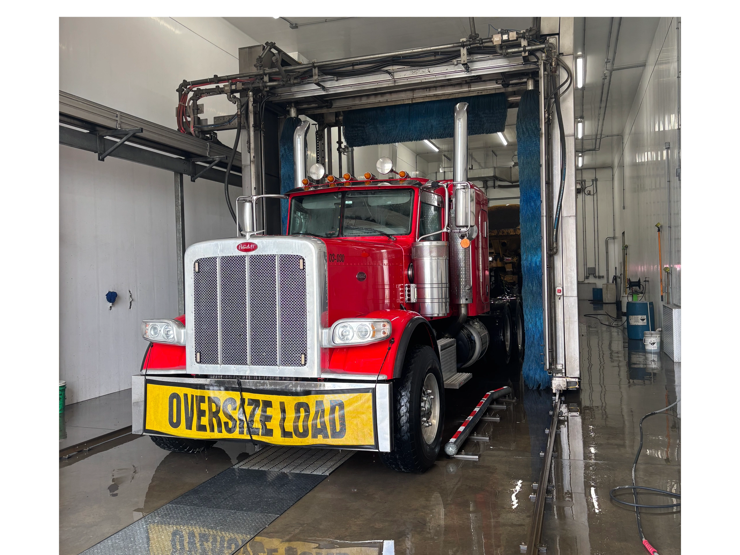 Peterbilt semi-truck in wash bay with oversize load sign
